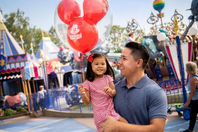Father and daughter smiling holding a balloon.