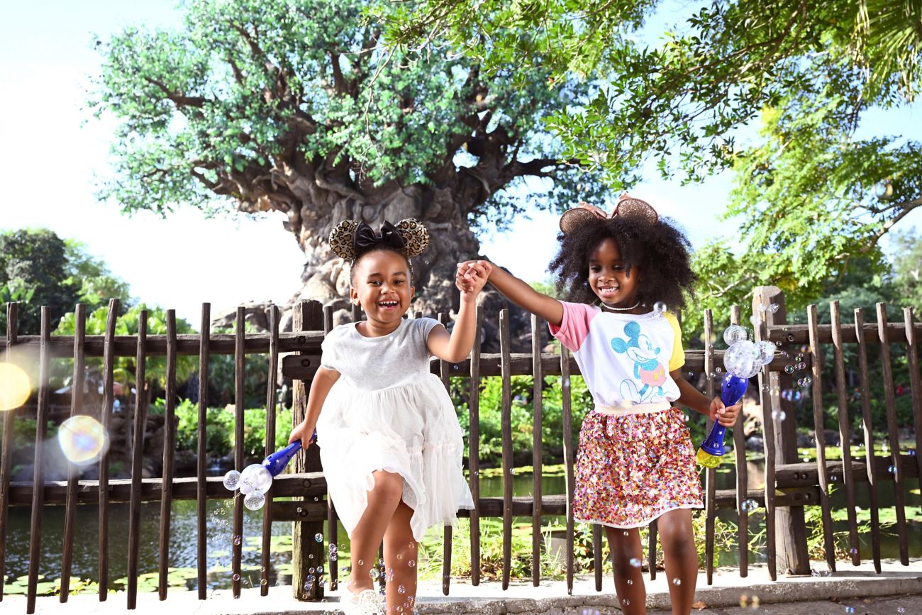 Two girls holding hands in front of Tree of Life.