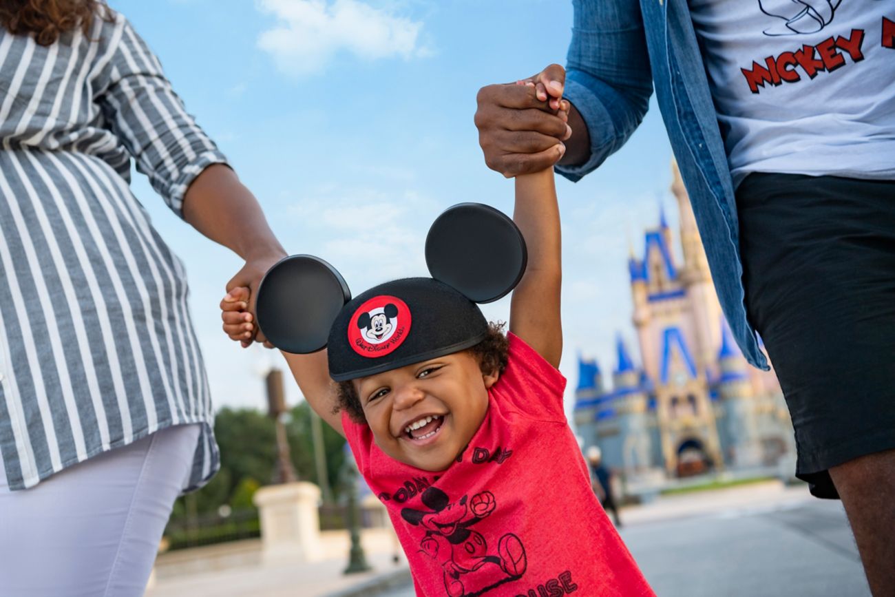 Boy wearing Mickey ears and smiling at Disney.