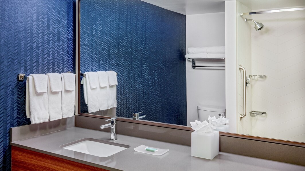 A bathroom with a sink, blue walls, and towels