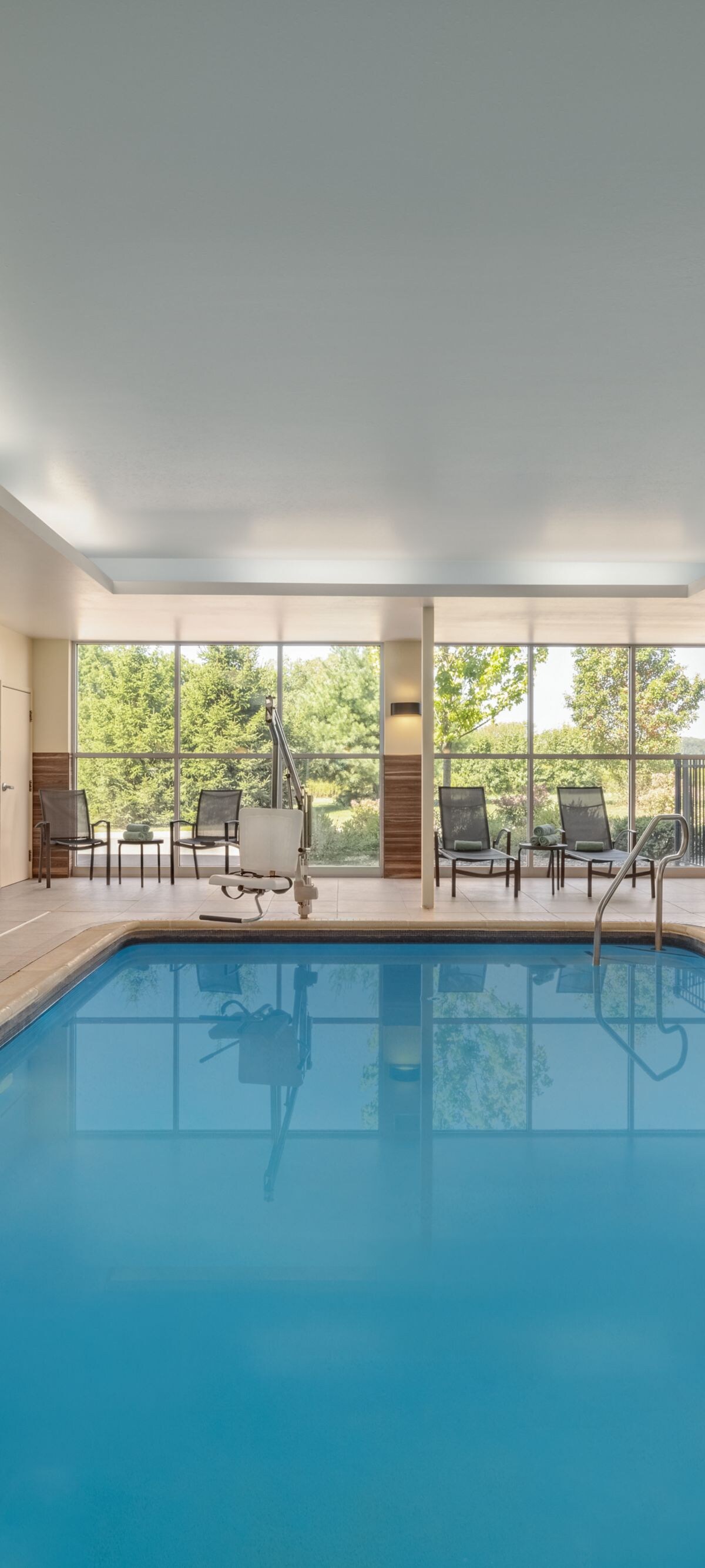 Indoor pool with lounge seating and large windows