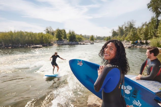 Woman smiling at camera as man rivers surfs