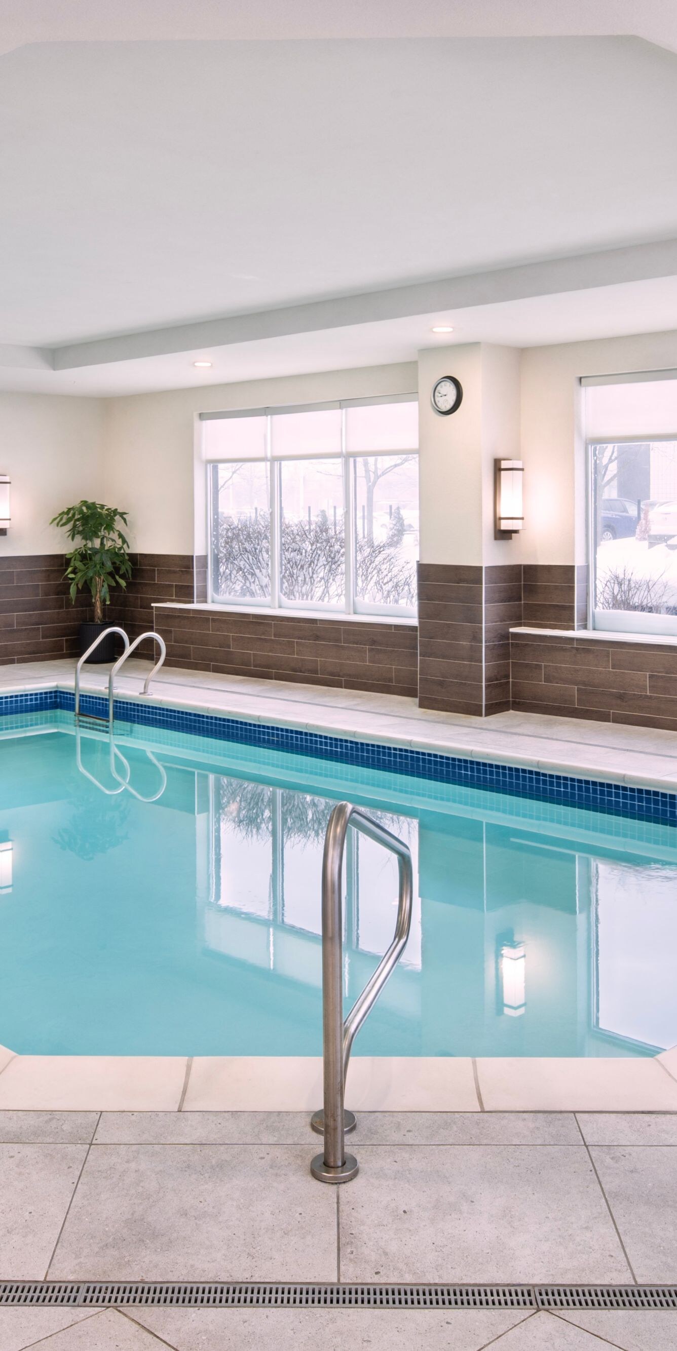Indoor pool with water feature and windows