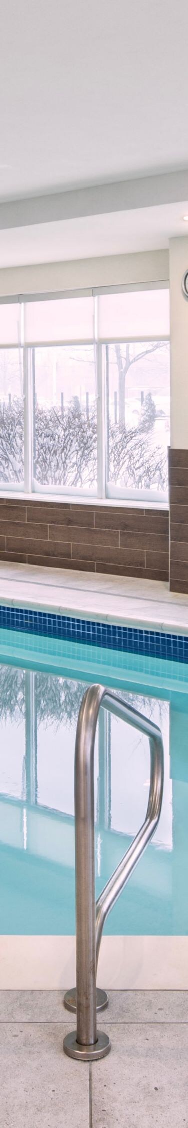 Indoor pool with water feature and windows