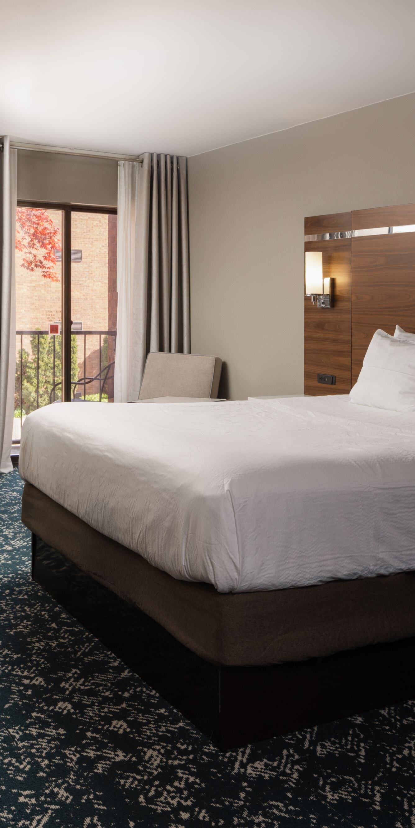 guest room with king bed, desk, and balcony