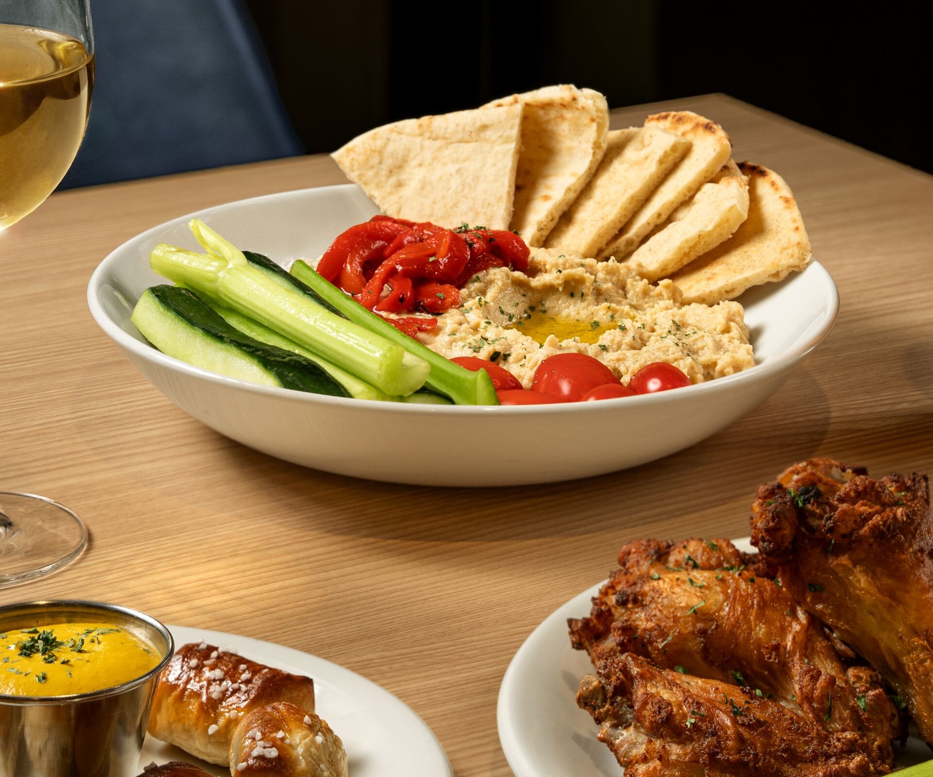 Hummus, pretzel bites, and wings with drinks