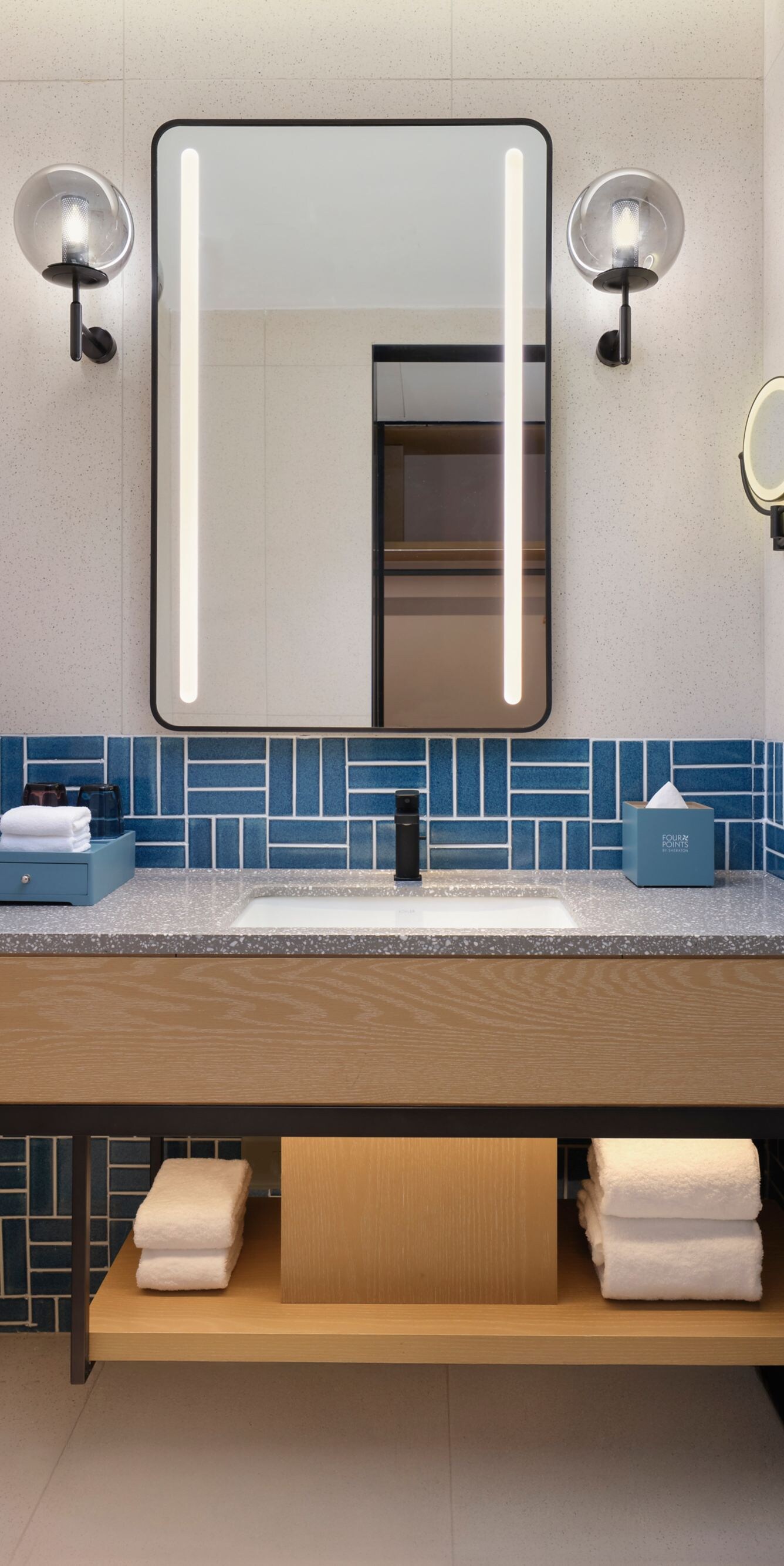 Light-toned hotel bathroom sink area with backlit 