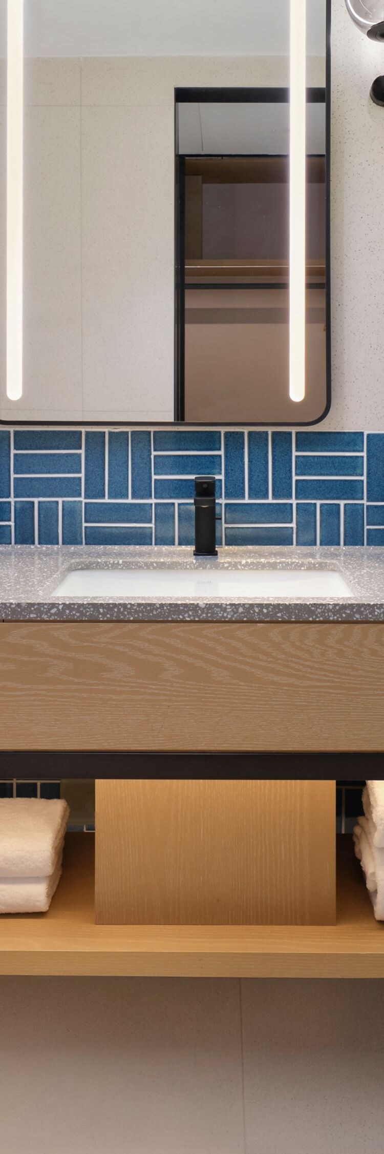Light-toned hotel bathroom sink area with backlit 