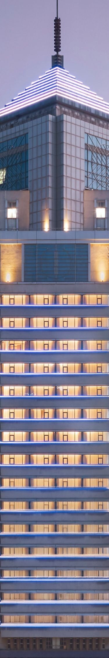 Tall glowing Four Points hotel tower against dusk 