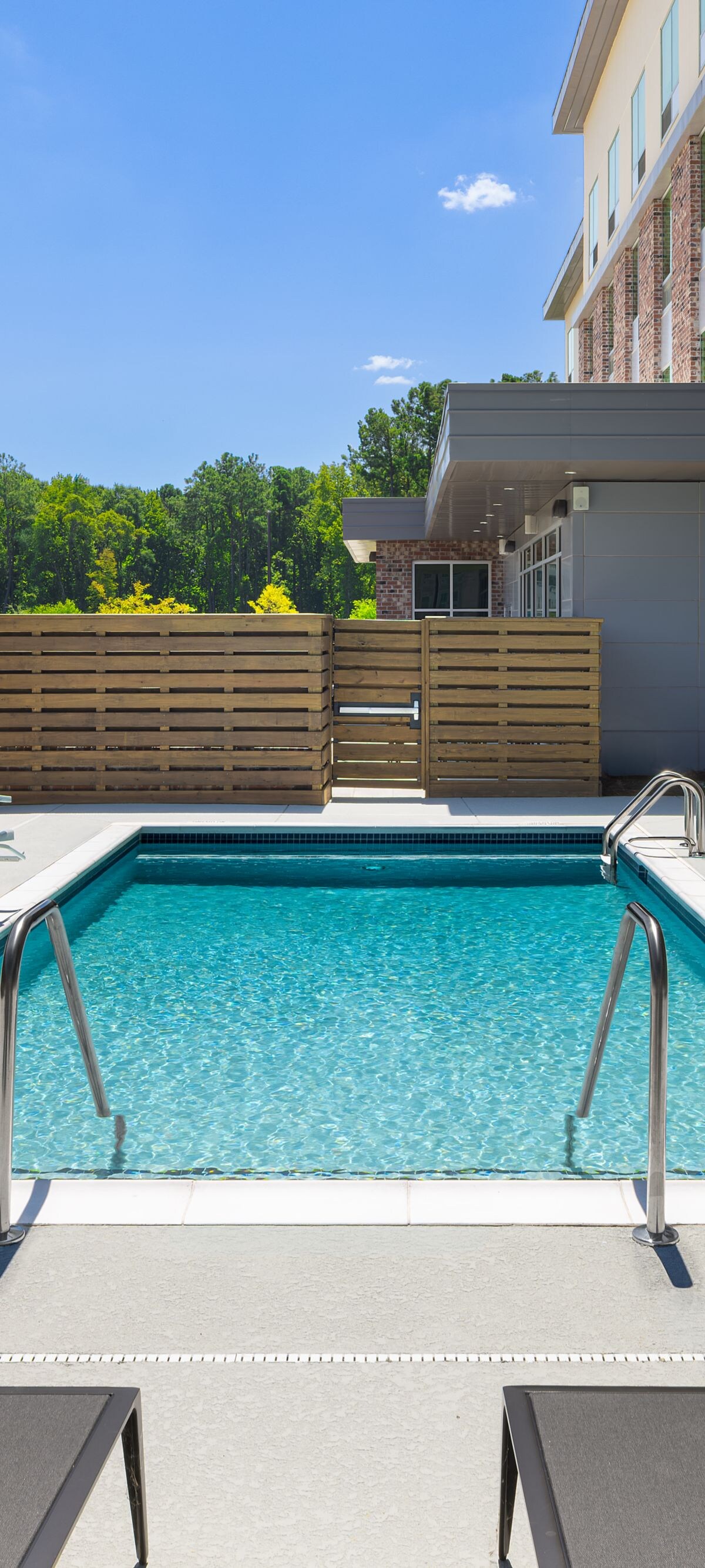 Outdoor pool has lounge chairs & accessible lift.