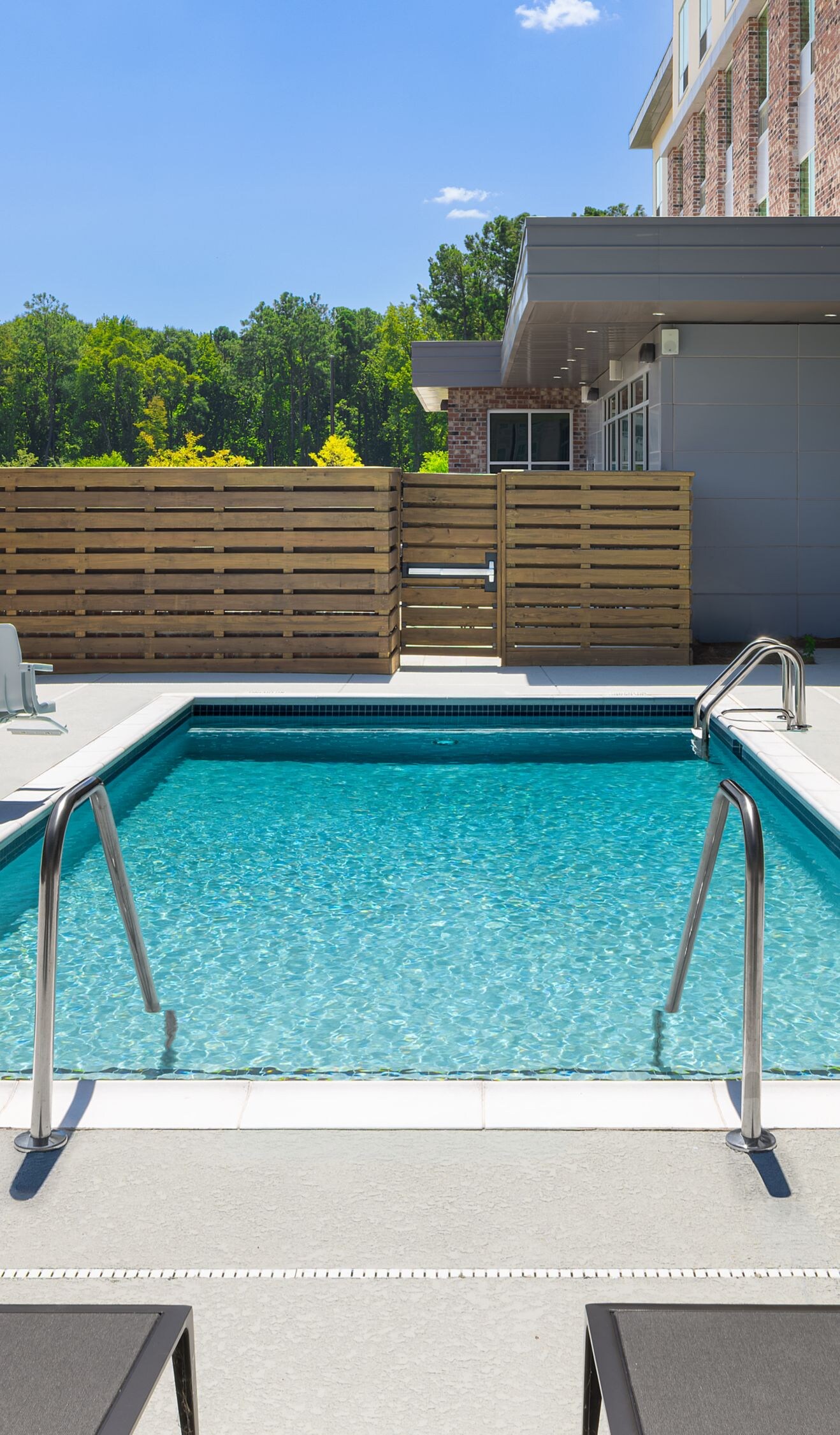 Outdoor pool has lounge chairs & accessible lift.