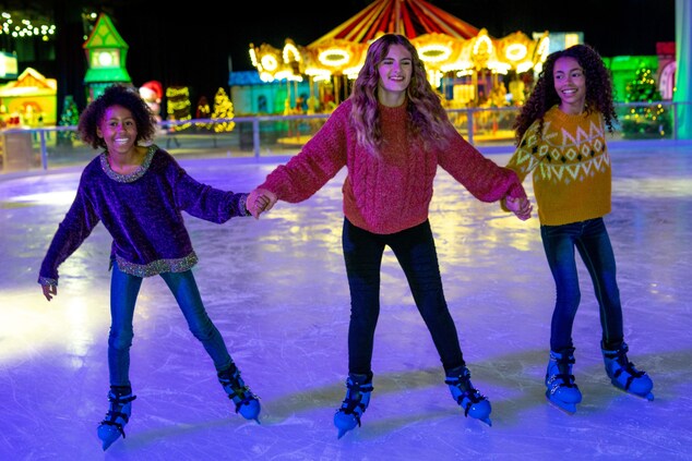 Três meninas patinando juntas no gelo.