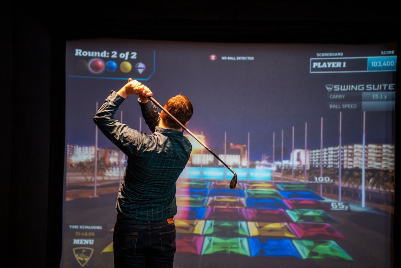 A man takes a swing at a virtual golf screen