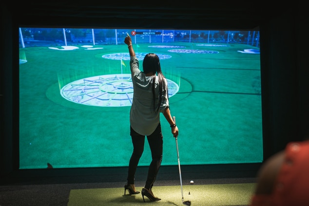 A woman in front of a large virtual golf screen