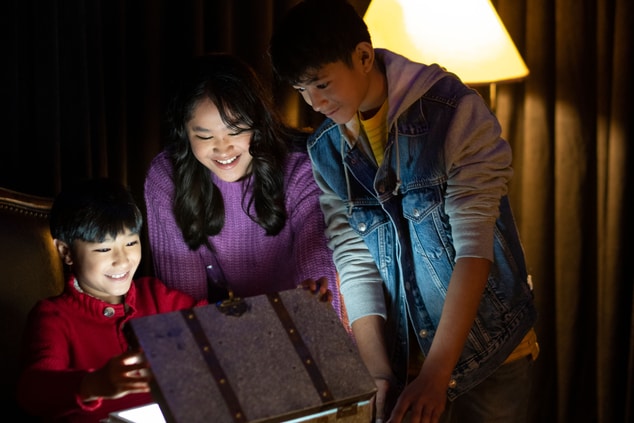Família abrindo caixa para ver uma luz brilhante em seu interior 