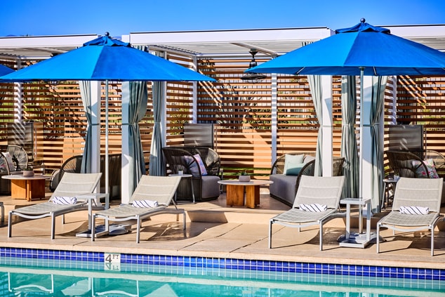 cabanas on a pool deck with loungers and umbrellas
