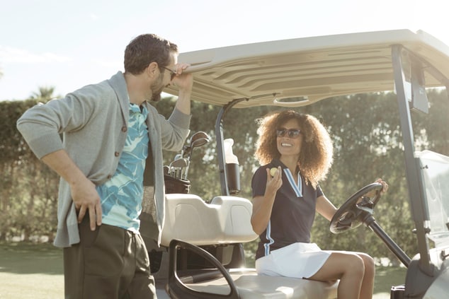 A man and woman talking in golf cart on course