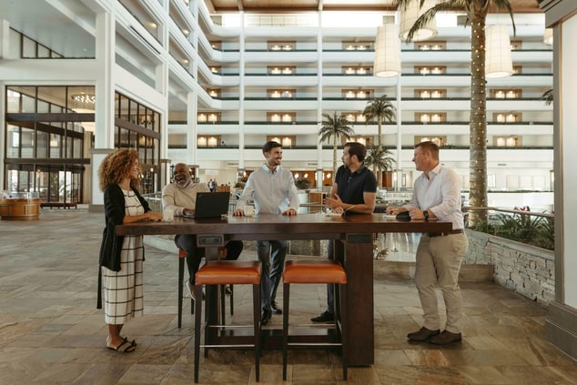 Five people standing around a communal table
