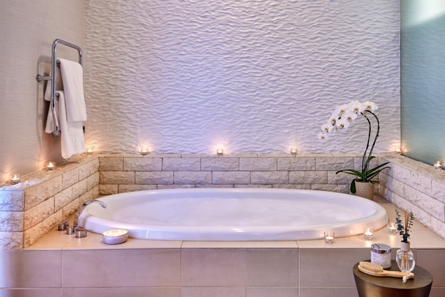 Relaxing white marble bathtub, candles and flower