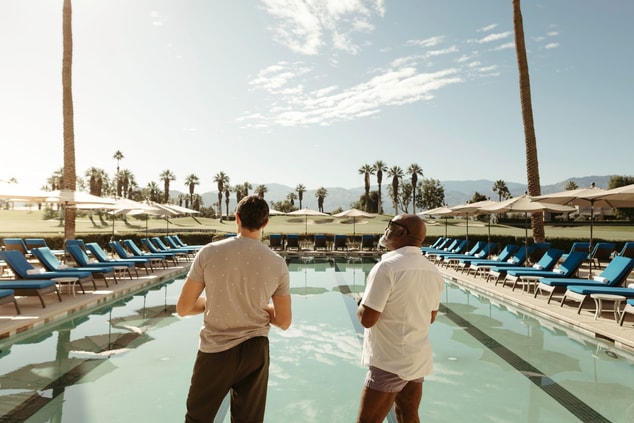 Two men standing in front of a spa pool with palm 