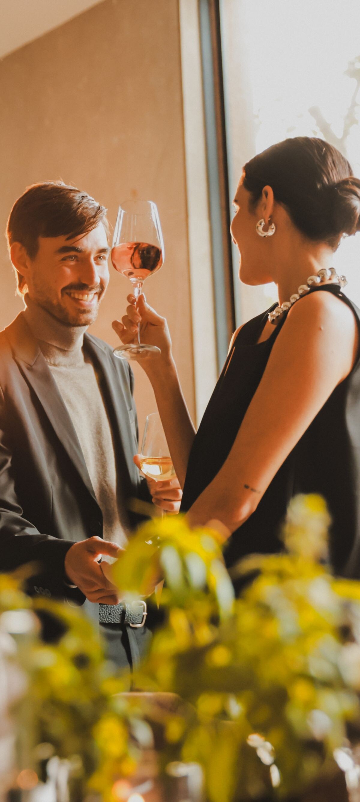 Dos personas en el interior sosteniendo copas de vino y plantas