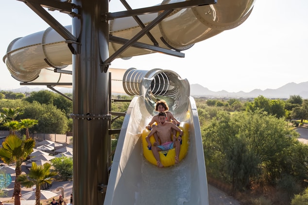 Two teens in double inner tube on slide