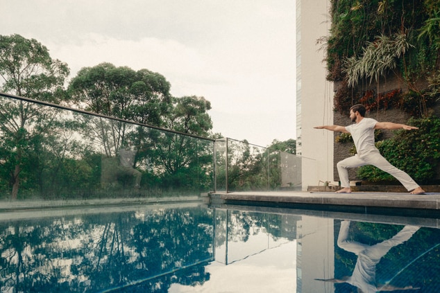 homem fazendo ioga à beira da piscina  