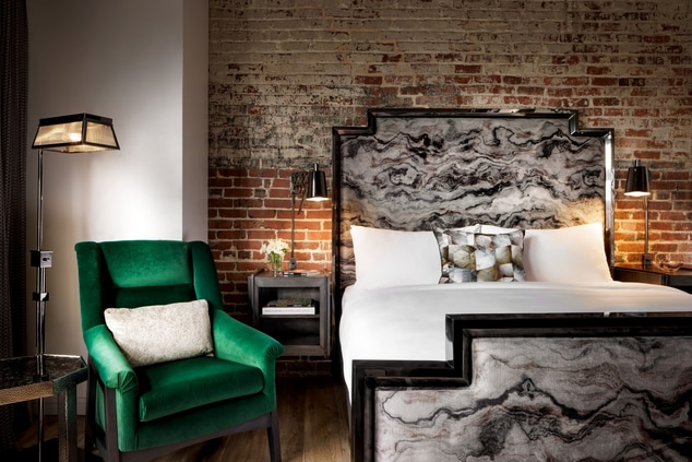 brick wall with green velvet chair and bed