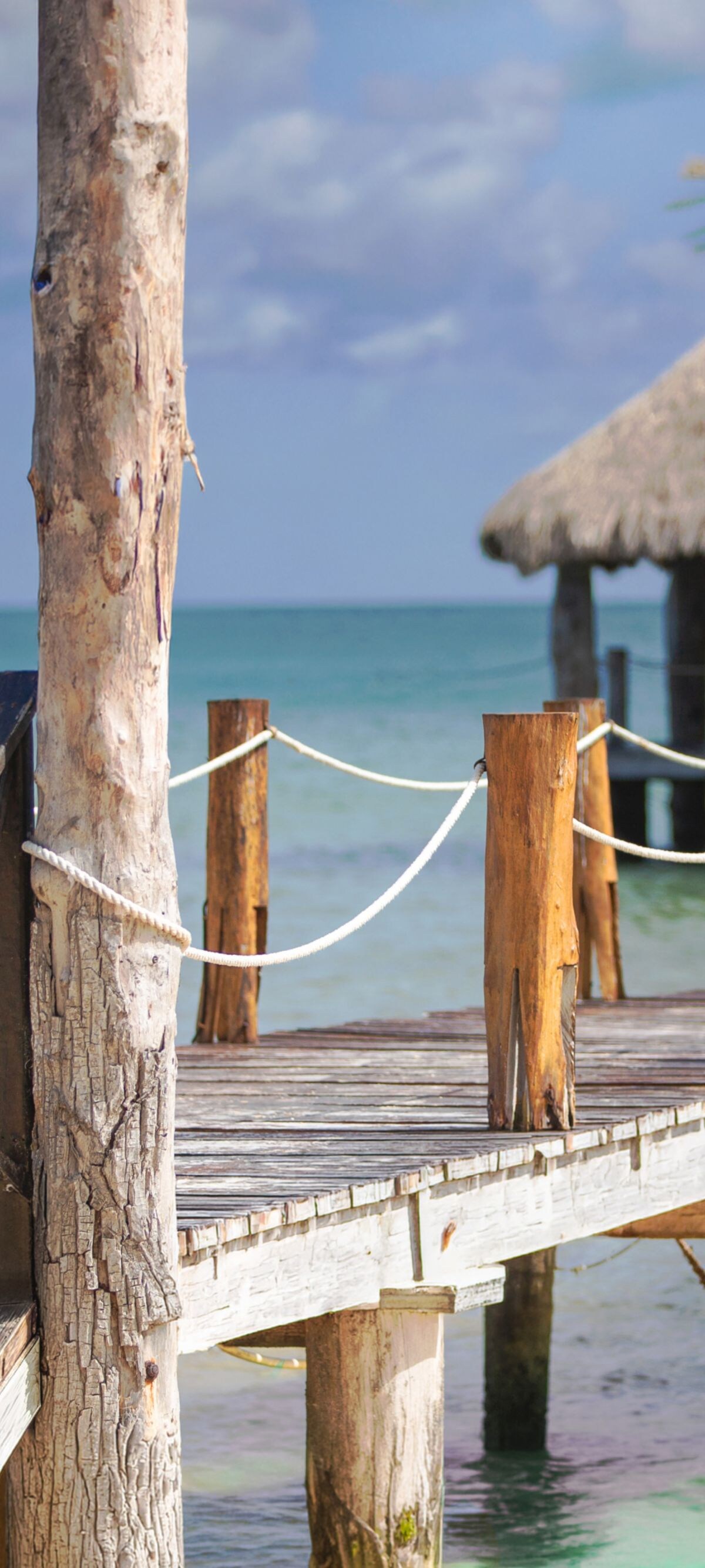 Muelle de madera que conduce a una cabaña de paja sobre el mar