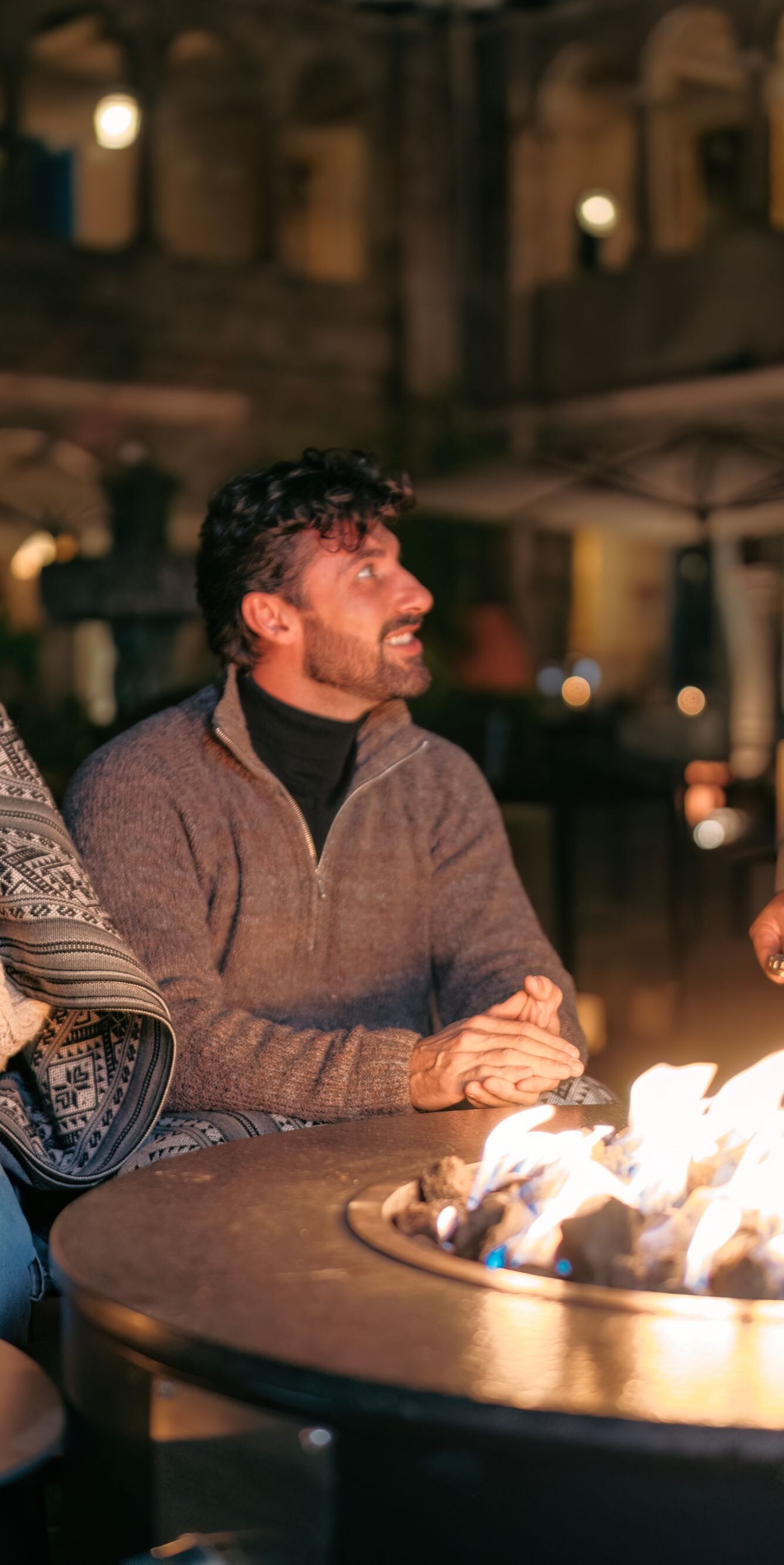 Couple sitting around firepit with cocktails