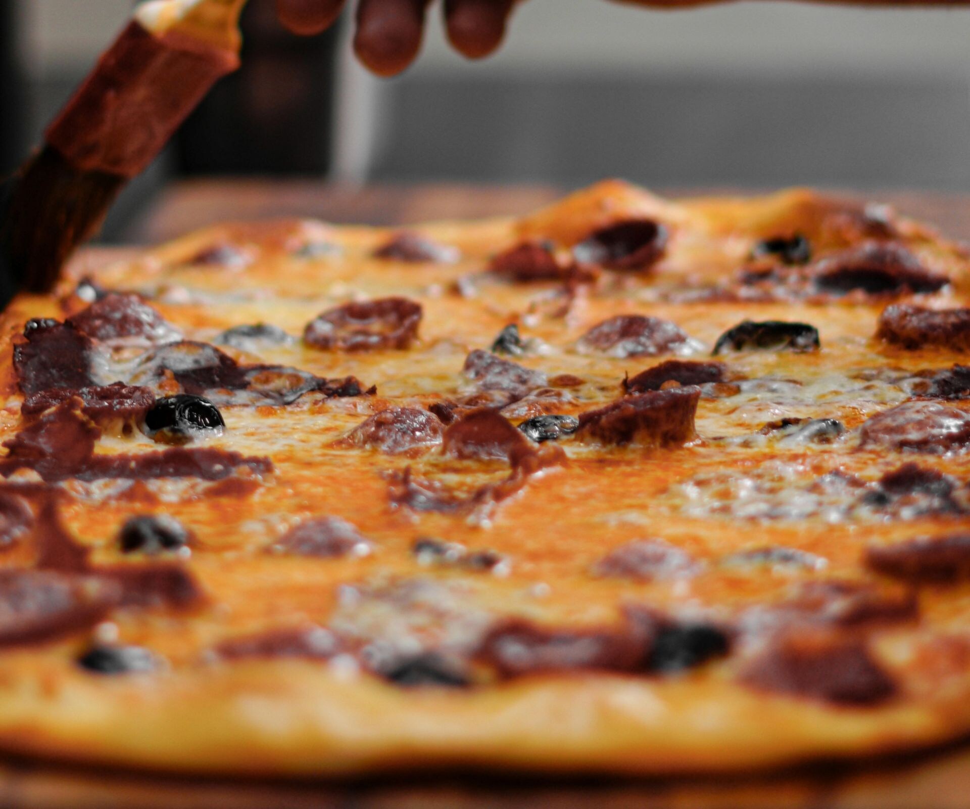 Odun fırınında pizzaya sos süren şef