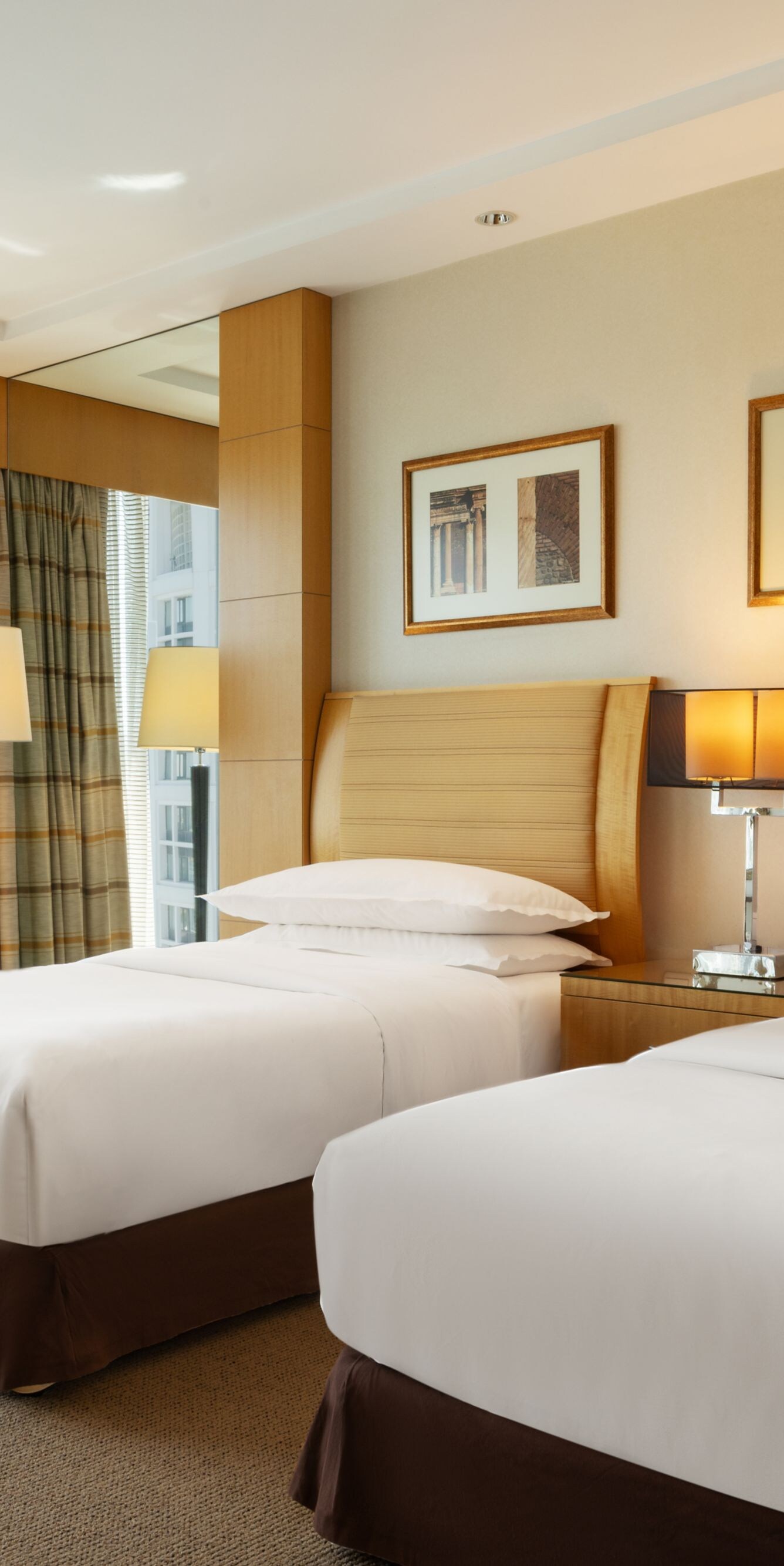 Twin beds beside floor-to-ceiling windows