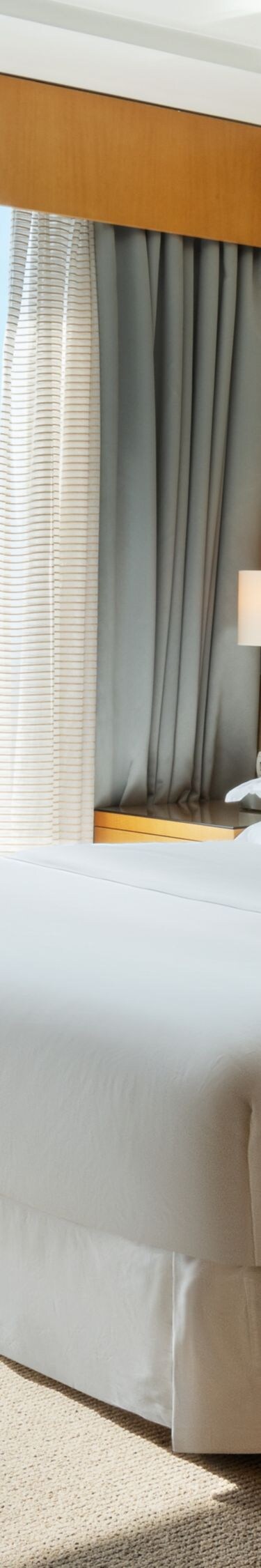 Queen bed beside floor-to-ceiling windows