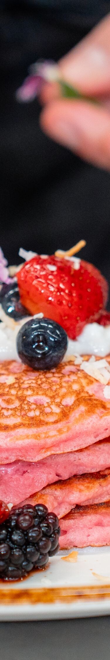 ピンクパンケーキの皿に飾り付けをするシェフ