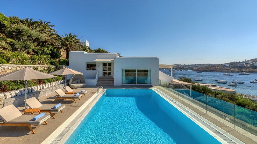 Villa con piscina y tumbonas con vistas al mar