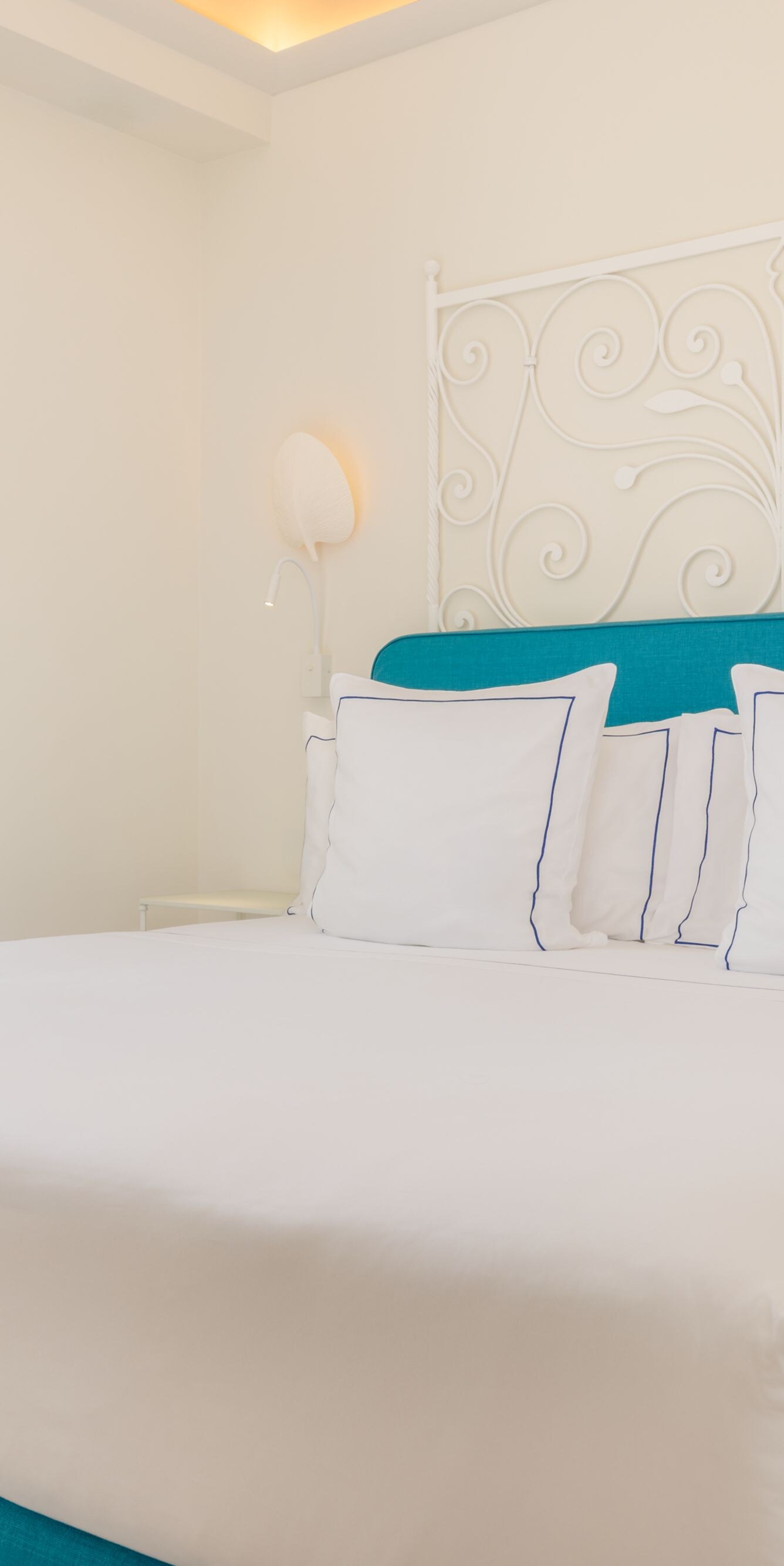 King bed with turquoise headboard and balcony door