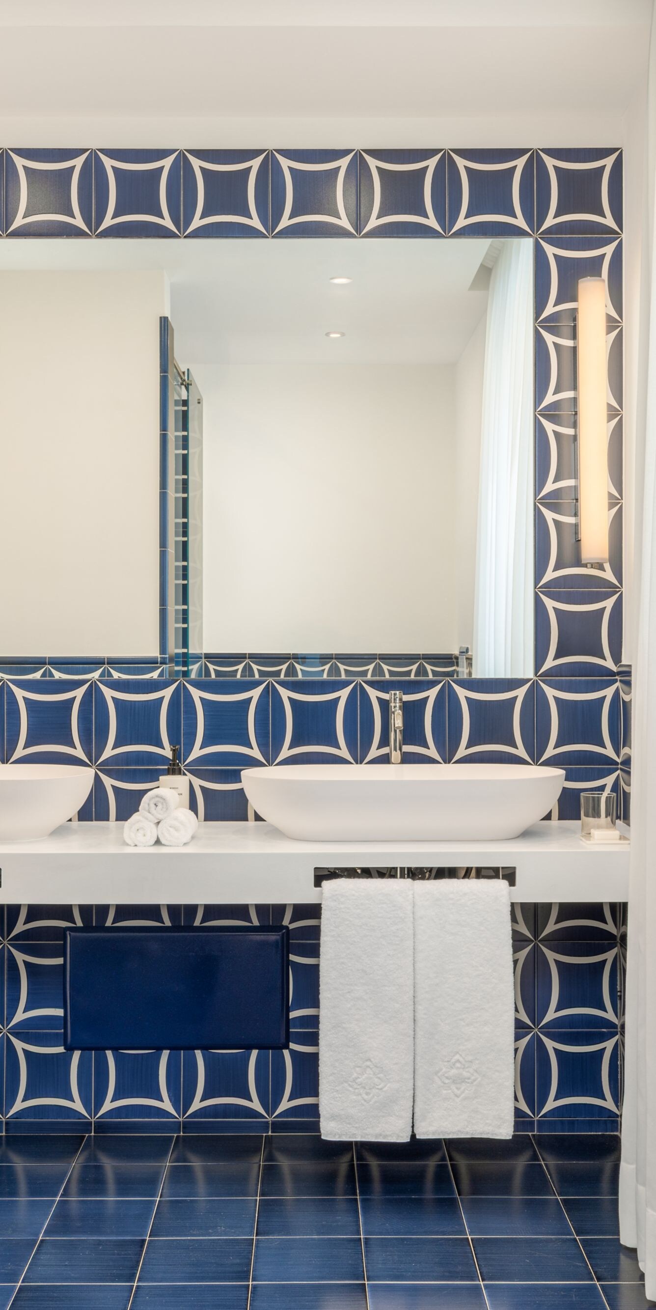 Blue tiled bathroom with double vanity and mirror