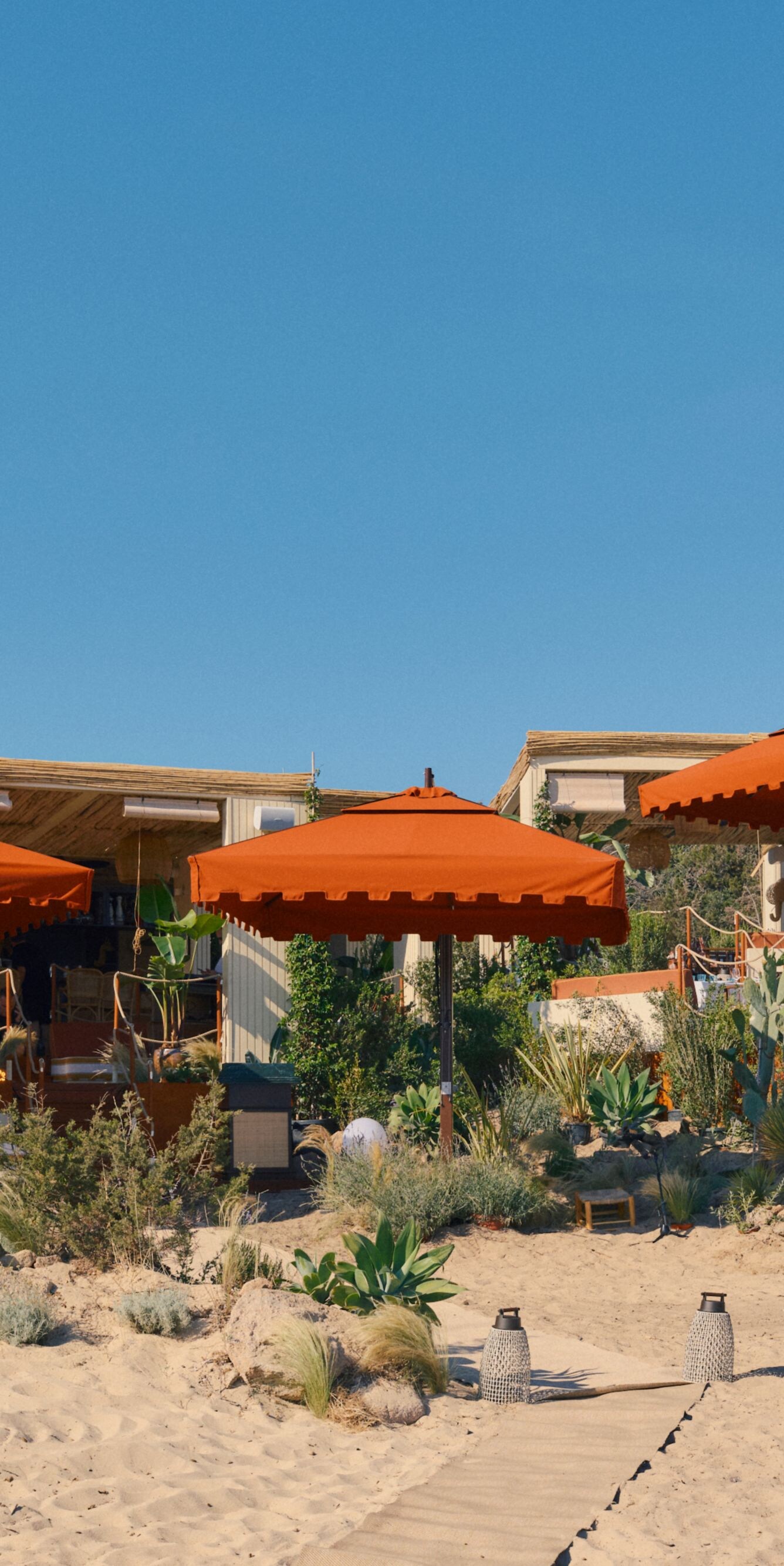 Beachfront cabanas with orange umbrellas and sandy