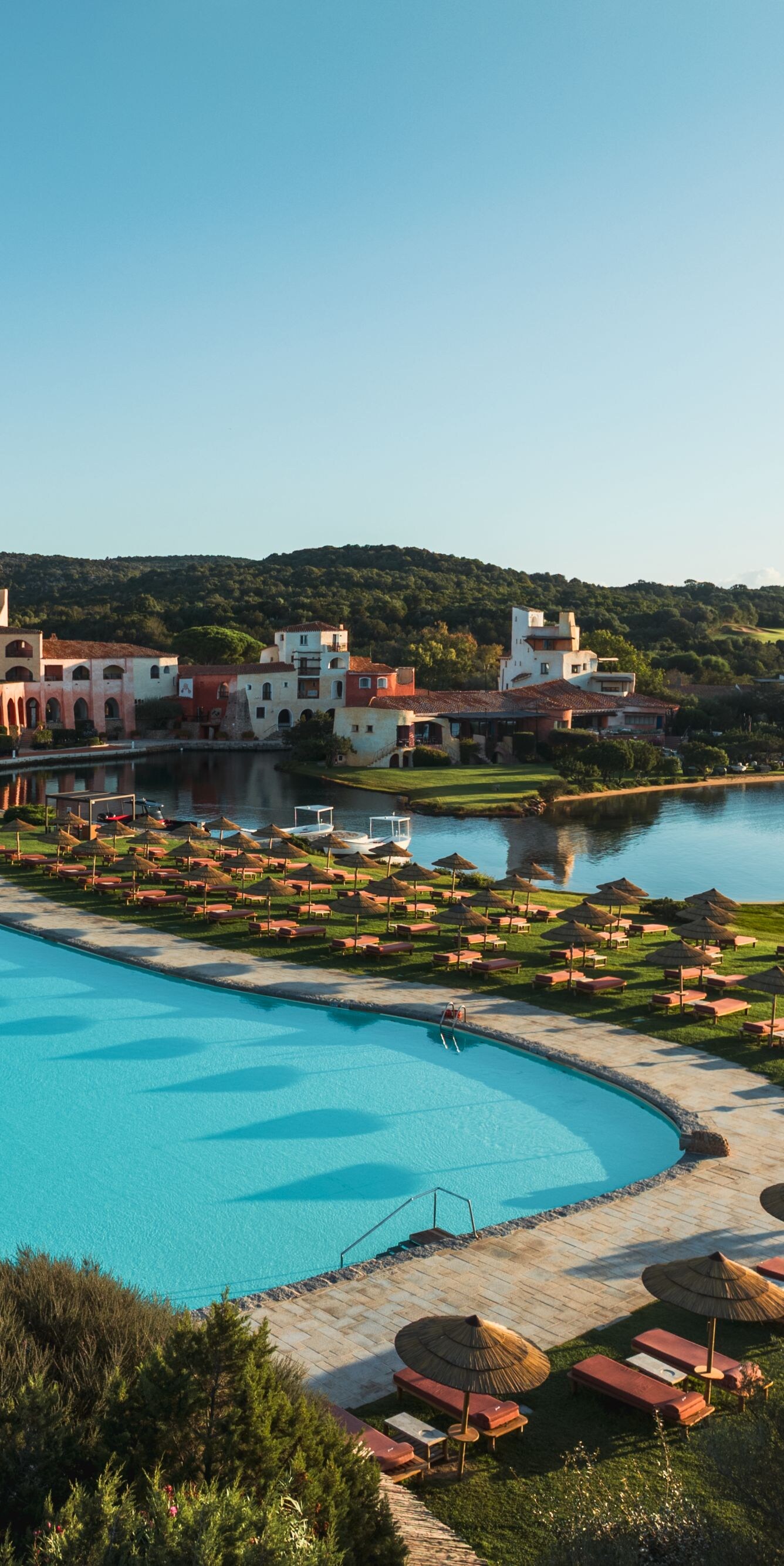 Resort pools beside lake with sun loungers