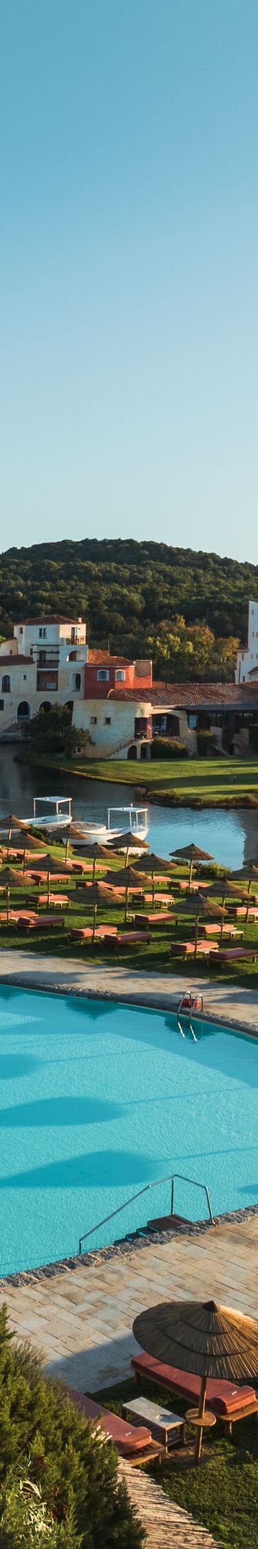 Resort pools beside lake with sun loungers