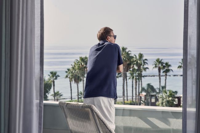 Man enjoying the serene view of the sea and palm t