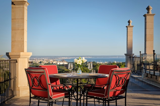Exterior table with red chairs, pillars, and views