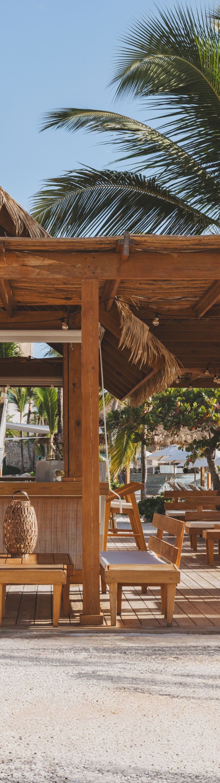 outdoor bar with thatch roof, chairs, and tables