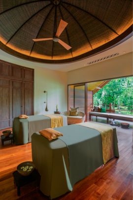 Spa suite with two massage tables and a private patio with views of the emerald foliage