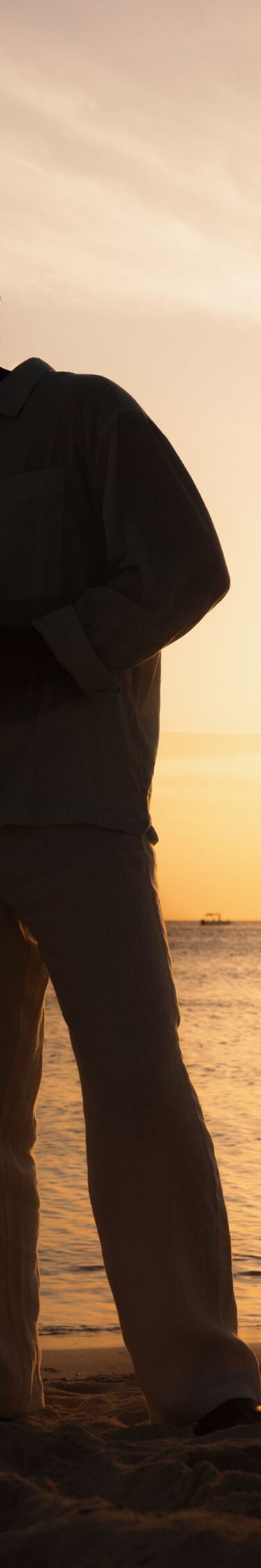 Two people standing on a sandy beach at sunset