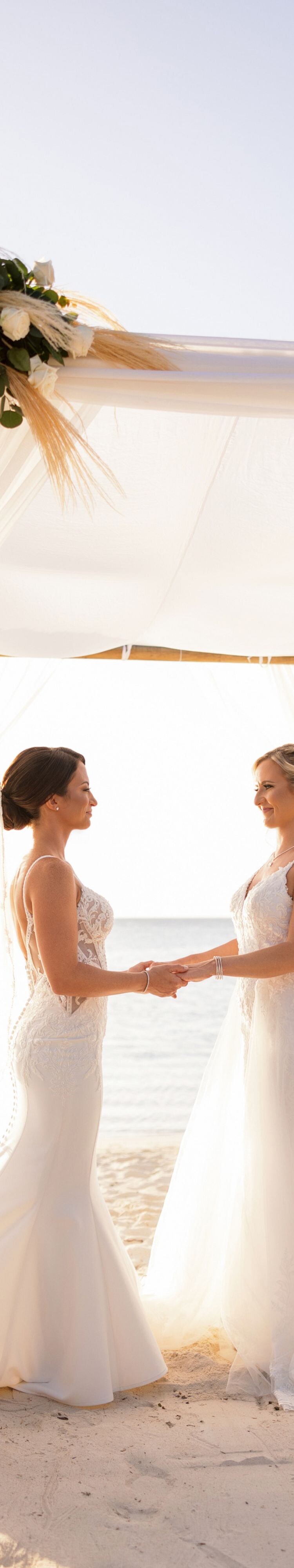 Two people in white wedding attire standing beneat