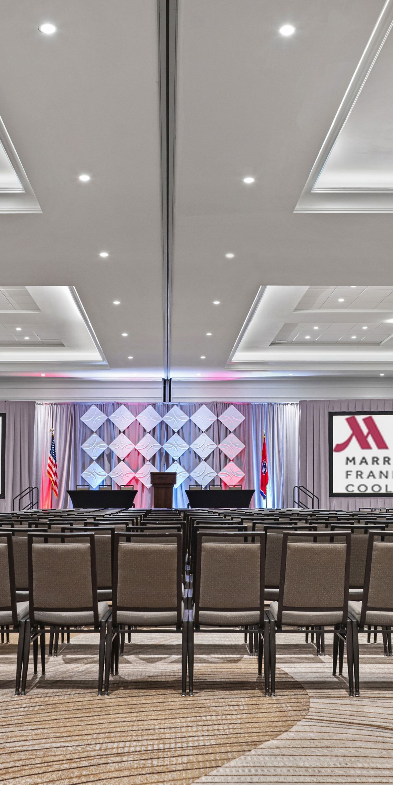 meeting room with rows of chairs and two screens