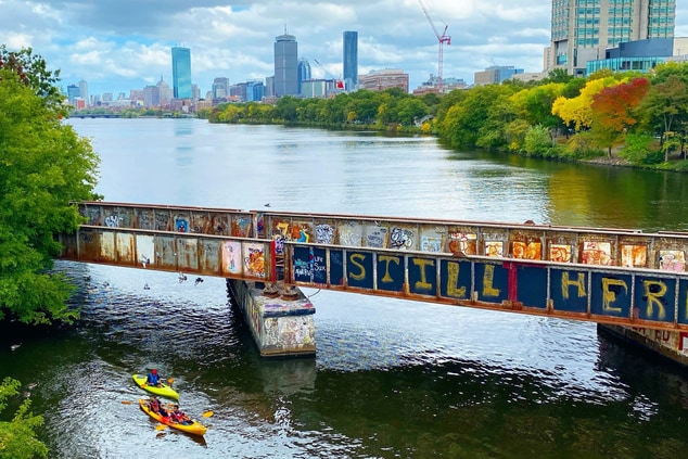 Graffiti lined bridge over river with canoe