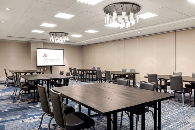 meeting room set up with square tables and a scree