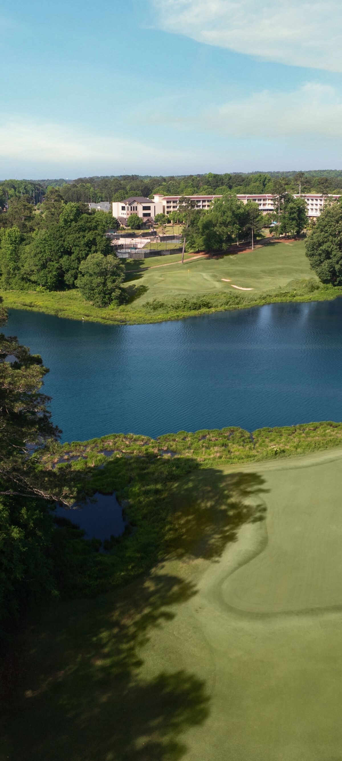 Golf course green with lake and forest